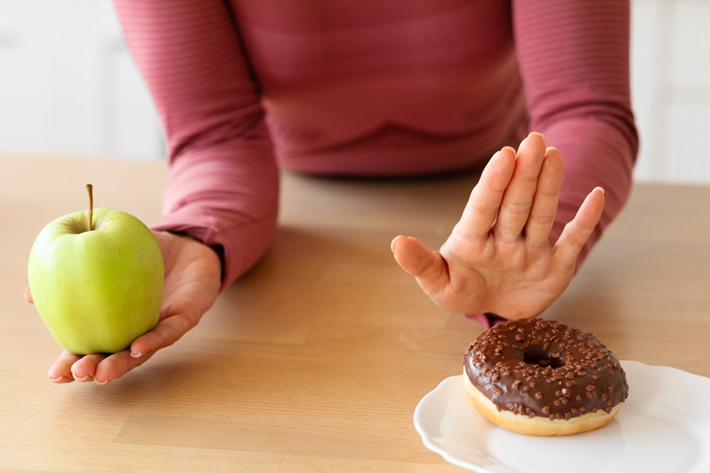 femme choisissant une pomme verte plutôt qu'un beignet